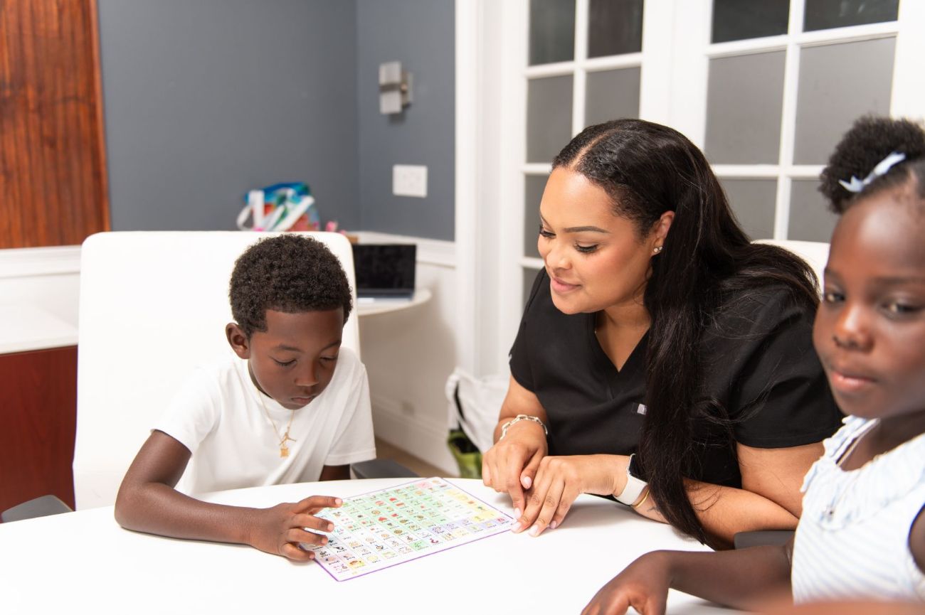 A therapist using a communication board with two children