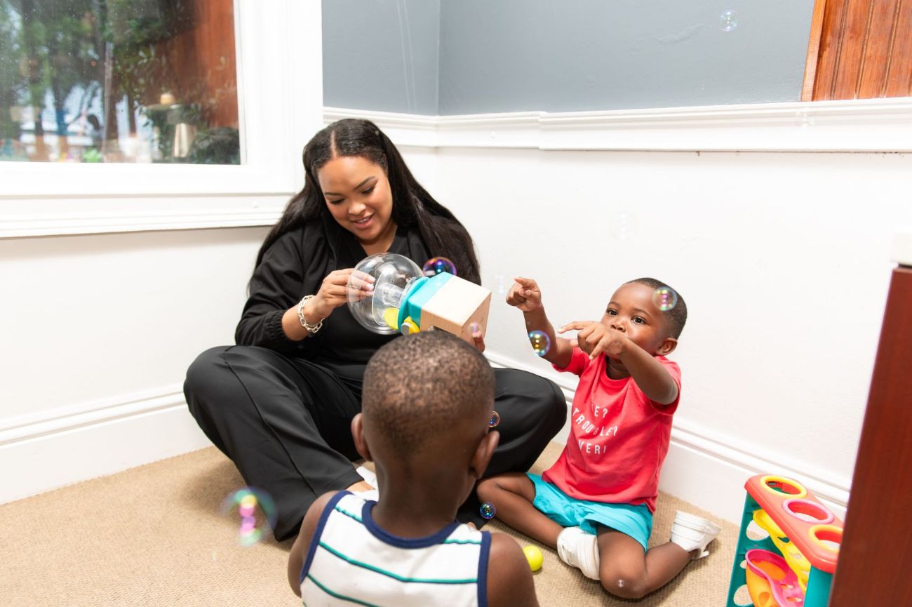 A therapist playing on the floor with two toddlers